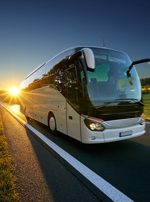 Motorcoach driving on road with sunset in background
